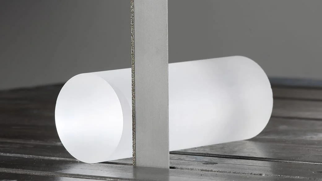 Taśma z nasypem diamentowym WIKUS DIAGRIT K przecinająca kruchy materiał niemetaliczny. Brak klasycznych zębów pokazuje, że jest to przecinanie ścierne, wymagające innego doboru ziarnistości, chłodzenia i sposobu podparcia niż cięcie metalu taśmą M42. Fotografia producenta: WIKUS — DIAGRIT K.